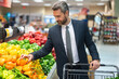 © Volodymyr - A man in a suit shopping in the supermarket. The well-dressed man with shopping cart selecting fresh groceries. The man pushes his shopping cart down the aisles. Man shopping in the grocery store.