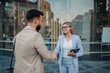 © Zamrznuti tonovi - Two business people shaking hands outside office building