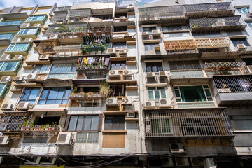a densely packed, older apartment building with numerous balconies, and air conditioning units in ma
