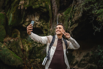 Wall Mural - Adult man hiker backpacker have video call on mobile phone