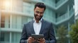 © NASSRI - Focused successful mature Indian or Latin entrepreneur businessman holding digital touchpad pc tablet standing outdoor at business office building. Hispanic smiling man in suit working using computer