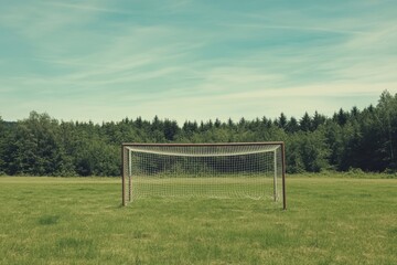 An empty football goal stands ready on a sunny summer day, awaiting eager players on a vibrant green field