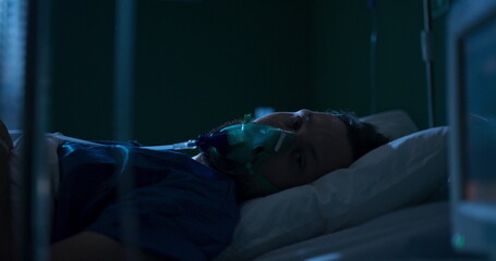 Man in hospital bed receiving oxygen through a mask.