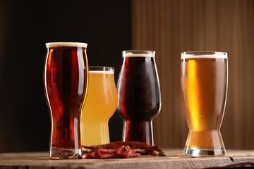 Wall Mural - Glasses with different types of beer and snacks on wooden table against color background