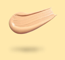 Canvas Print - Skin foundation in air on beige background. Cosmetic product