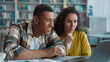 © Yuliia - Two people African American man Indian Arabian woman team joy victory win students session diploma exam together classmates achievement laptop screen give five girl guy library good grade university