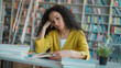 © Yuliia - Tired Latino arabian woman sitting reading book studying knowledge exam preparation lesson lecture session student girl female library boredom intelligence education desk college learning university
