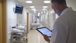 © aubriella - A healthcare worker using a tablet to review patient information in a modern, sleek hospital room, Tech-savvy style