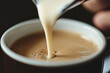 © jr-art - A person is pouring milk into a cup of coffee