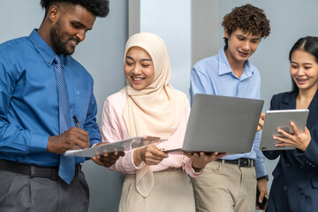 Diverse group of business professionals in formal collaborating during a corporate meeting, focused on technology and teamwork, asian businesswoman leading with laptop, teamwork and collaboration