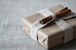 © Pui - A simple gift wrapped in natural brown paper, A beautifully wrapped gift box with cinnamon sticks and twine, perfect for holiday celebrations and special occasions.