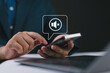 © Nirusmee - Silent mode concept. Silent or mute sound icon turn activated on appear in speech bubble on mobile smart phone in hand while business person work with laptop computer on desk in office or workplace.