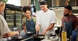 © CineLens2024/peopleimages.com - Cooking, class and chef in kitchen with group for meal preparation, teaching gourmet recipe or learning skills. Culinary course, people and mentor with lesson on food education and cuisine knowledge