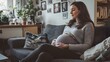 © Berkah - Young pregnant woman sitting on couch in living room.