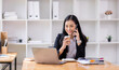 © David - asian woman talking on the phone while working on computer in desk office. Searching on internet