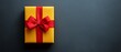 © Hryhor Denys - A brightly wrapped yellow gift box with a red ribbon is positioned on a dark surface, capturing the spirit of Black Friday shopping excitement