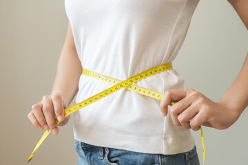 Diet, slim shape asian young woman standing, hand using measure tape around waist, body. Happy, pleasure girl slim slender on white background. Diet session for wellbeing health, eat good food people.