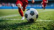 © sknab - A close-up of a soccer ball rolling on the grass while players in red uniforms are in action during a match.