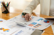 © Wicitr - Financial Analyst at Work: Close-up shot of a woman's hands meticulously reviewing financial data, surrounded by charts, graphs, and a calculator.  The image conveys focus, precision.