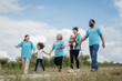 © VStudio - A group of people wearing blue shirts are walking together. The group includes a man. environment, clean, wind turbine, volunteer, community, teamwork, social, care, nature