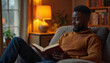 © ON - Studio - Black man reading book in cozy living room with warm lighting.