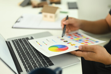 An interior designer reviewing a color chart while working on new design project at a desk