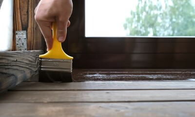 close-up of a brush painting wood floor in brown color. wood plank impregnation. finish oil coating 