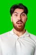 © fotofabrika - Surprised young man with a beard expressing shock against a bright green background