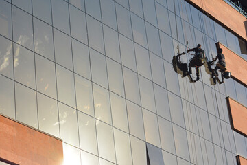 Building windows cleaner. A group of workers cleaning windows of a modern office building with scaffolding.