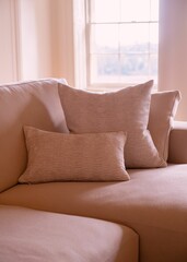 Wall Mural - Cozy beige sofa with textured pillows by a window.