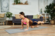 © LIGHTFIELD STUDIOS - A young brunette woman works out on a yoga mat at home, focusing on her fitness routine in a comfortable environment.