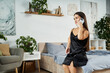 © LIGHTFIELD STUDIOS - A petite brunette woman relaxes at home, sitting on her bed and engaging in a cheerful phone conversation.