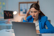 © Tj - Stressed asian businesswoman works late in her office, analyzing data on her laptop as city lights shine through the window, highlighting corporate pressures