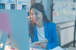 © Tj - Dedicated businesswoman works late into the night, smiling and chatting on a headset, showcasing professionalism and commitment