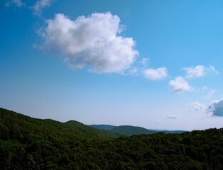 Scenic view of lush green mountain landscape under a bright blue sky with fluffy clouds in Croatia