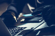 © Tomasz Zajda - Criminal Using a Computer to Commit Fraud With a Credit Card at Night in a Dimly Lit Room