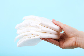 Baby diapers with female hand on blue background