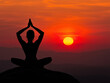 © Ionia - Silhouette of a person practicing yoga at sunset, with a vibrant red sky and glowing sun in the background