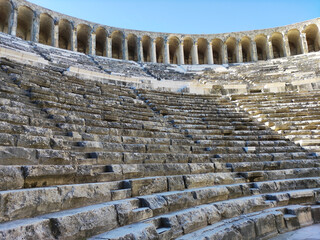 An ancient ruined amphitheater of the Roman period, with stone walls, columns, arches and stairs