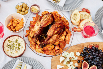 Vibrant top view background of delicious grilled chicken with roasted potatoes on festive dinner table shot with flash