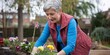 © hobonski - Senior Woman Gardening in Backyard. A happy senior woman wearing gardening gloves and an apron tending to colorful pansies in a raised garden bed in her backyard.
