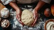 © familymedia - Hands are kneading a ball of dough on a floured surface, surrounded by bread and other baking ingredients in a cozy kitchen setting, emphasizing baking art.
