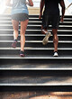 © peopleimages.com - Fitness, people and legs with running on stairs outdoor for marathon training, cardio exercise and teamwork. Back, athlete and runner with morning jog on steps for competition workout and endurance