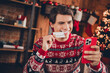 © deagreez - Photo of handsome good mood guy wear print sweater celebrating noel xmas ordering gifts modern device indoors room home house