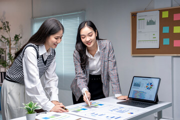 Two businesswomen discussing over business report in modern office