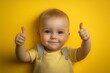 © Kristina - a toddler giving a thumbs up on yellow background