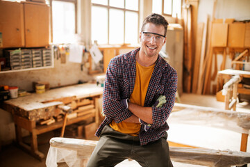 Portrait of a young carpenter looking at the camera in his woodworking workshop