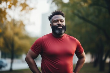 Portrait of a middle age body positive african american man in sporty clothes smiling after running in the city park