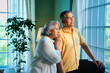 © StockImageFactory - Mature Indian couple standing near a big window, bathed in morning light, looking outside seriously