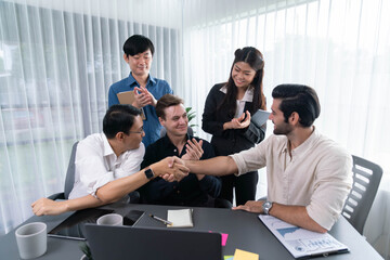 Diverse group of office employee worker shake hand after making agreement on strategic business marketing meeting. Teamwork and positive attitude create productive and supportive workplace. Prudent